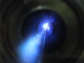 In an experiment to simulate what happens when sunlight hits Titan's atmosphere, UA researchers put nitrogen and methane gas into a stainless steel cylinder and zapped it with high-energy UV light. The nitrogen molecules emit blue light when zapped by the UV light. The white in the picture surrounds the pinhole opening that is the source of the UV beam. (Credit: Hiroshi Imanaka, University of Arizona; Click to enlarge) In an experiment to simulate what happens when sunlight hits Titan's atmosphere, UA researchers put nitrogen and methane gas into a stainless steel cylinder and zapped it with high-energy UV light. The nitrogen molecules emit blue light when zapped by the UV light. The white in the picture surrounds the pinhole opening that is the source of the UV beam. (Credit: Hiroshi Imanaka, University of Arizona; Click to enlarge)